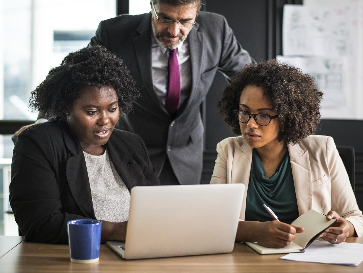 A leadership team reviewing work on a laptop